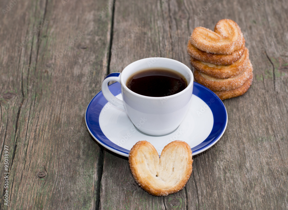 coffee on a saucer, and a column from cookies, on a wooden table coffee on a saucer, and a column from cookies, on a wooden table
