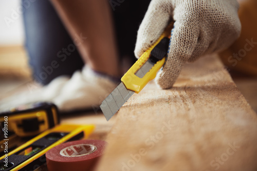 Male carpenter hand holding cutter sitting on the floor with instruments. Concept of home improvement and woodwork. photo