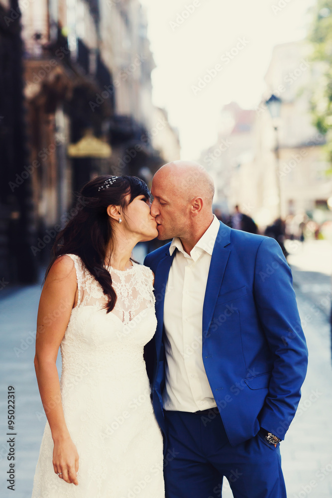 bald groom and bride brunette kissing on the streets of the old bald groom and bride brunette kissing on the streets of the old