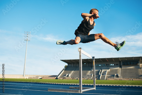 Professional sprinter jumping over a hurdle photo