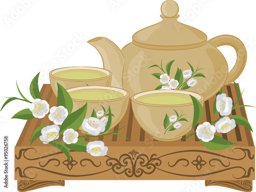 Kettle, small cups of green tea on a wooden table and flowers of tea. Set of isolated objects.