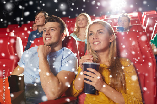 happy couple with popcorn and drink in cinema