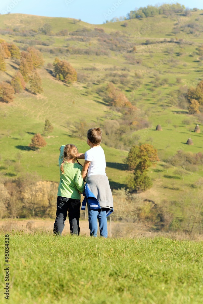 Brother and sister stand on the hill and admire the scenery of autumn