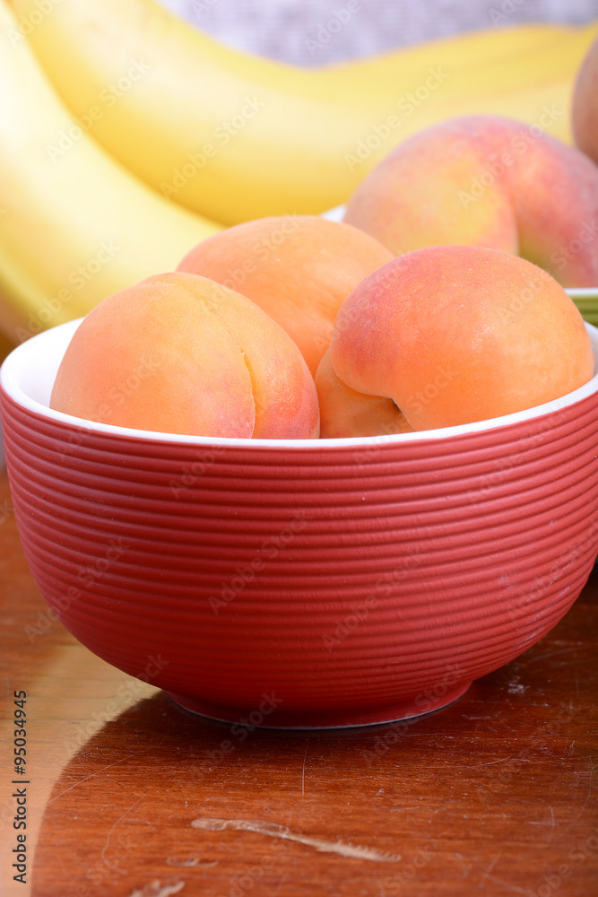 bananas and apricots on red plate, close up bananas and apricots on red plate, close up