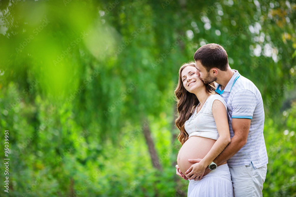Happy young couple expecting baby in summer park Happy young couple expecting baby in summer park