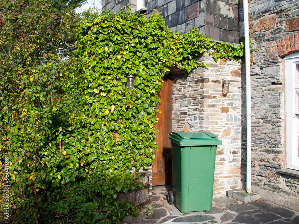 Naklejka premium Green wheelie bin in front of a house entrance somewhere in Port Isaac in north Cornwall