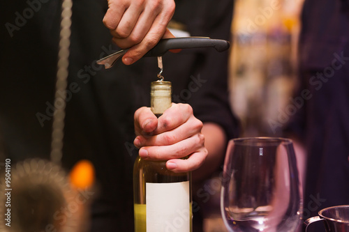 Opening a wine bottle with corkscrew  photo