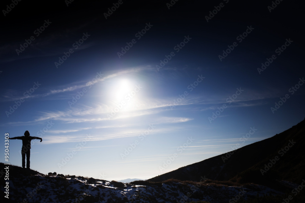 Silhouette of a girl on top of a mountain.