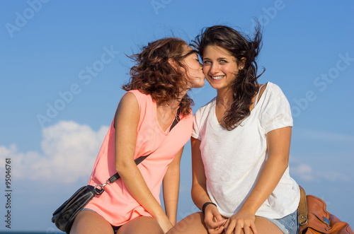 Girl kissing her girlfriend and looking at the camera - caucasian people