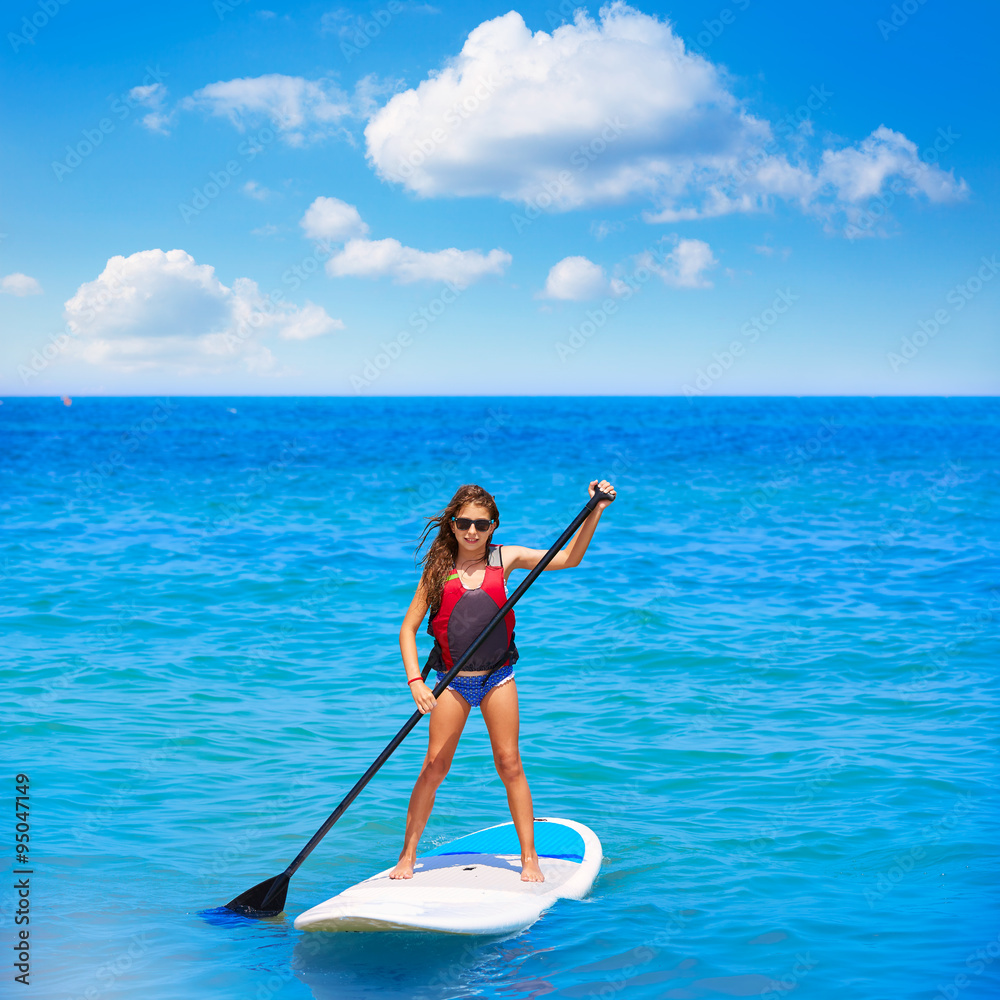 Kid paddle surf surfer girl with row in the beach Kid paddle surf surfer girl with row in the beach