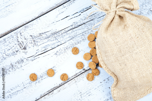 Dutch candy pepernoot with jute bag on white blue wooden background