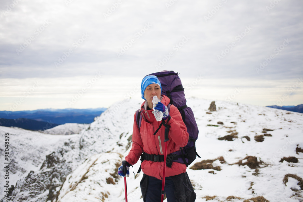 A girl drinks water at the top of high mountains.
