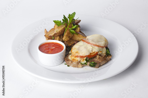 roasted meat with tomatoes and mayonnaise, potato wedges in the peel plate isolated white background menu