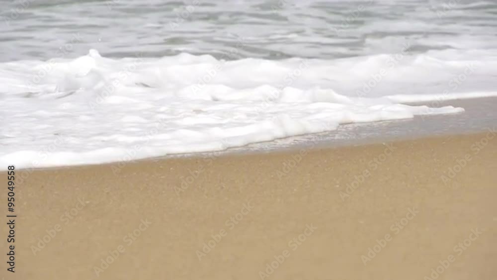 SLOW MOTION: Sea foam slides along the sandy beach SLOW MOTION: Sea foam slides along the sandy beach