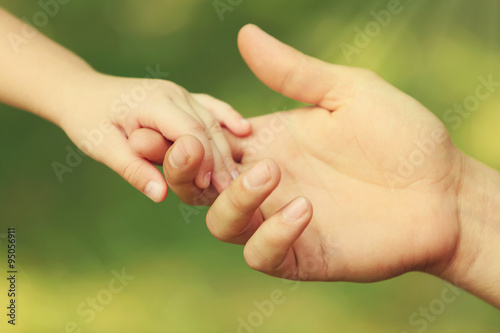 Father's hand lead his child daughter outdoors on green defocused background, trust family concept © Africa Studio