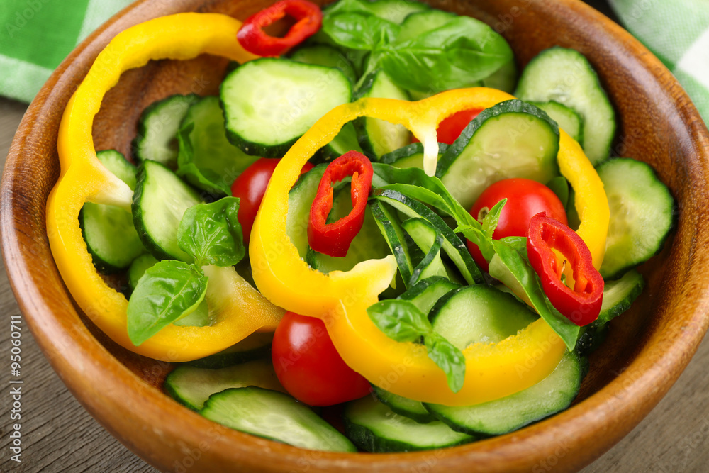 Vegetable salad with cucumbers on wooden background decorated with green checked cotton serviette and sweet pepper Vegetable salad with cucumbers on wooden background decorated with green checked cotton serviette and sweet pepper
