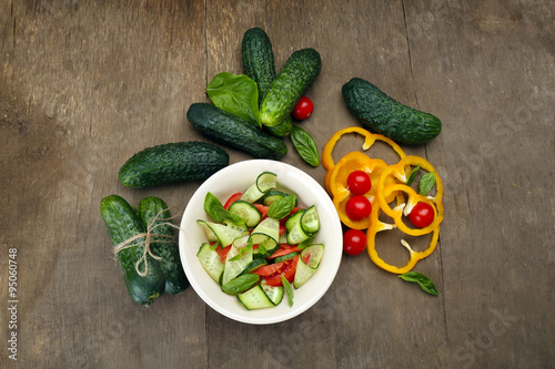 Vegetable salad with cucumbers and pepper on wooden background