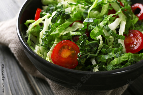 Savoy cabbage and tomato salad served in bowl on wooden table