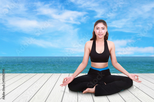 woman doing yoga exercise on wood floor with sea and sky