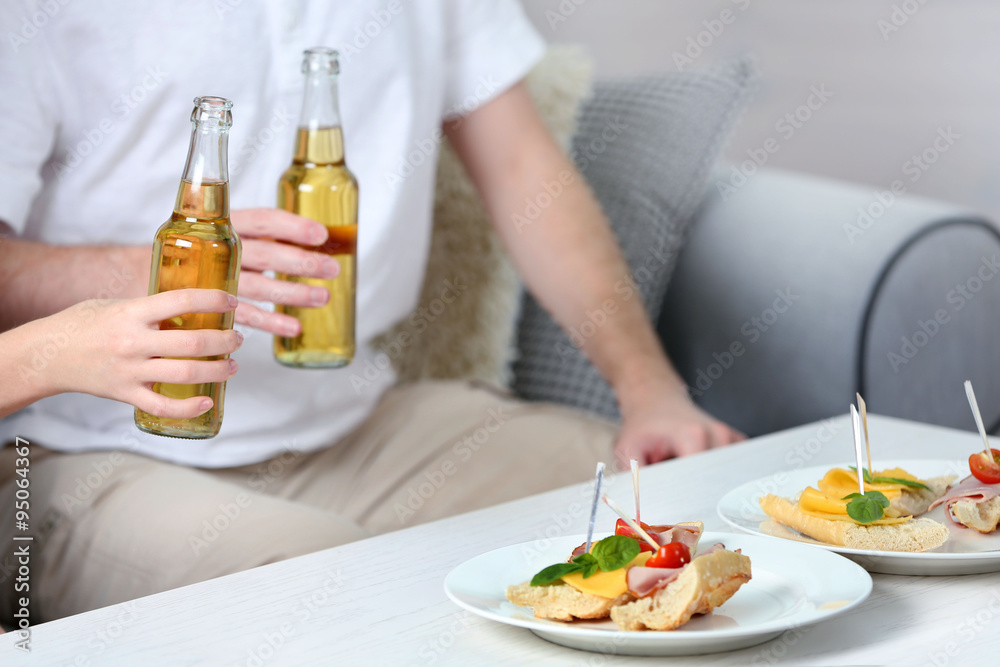 Friends hands with bottles of beer and snacks , close up Friends hands with bottles of beer and snacks , close up