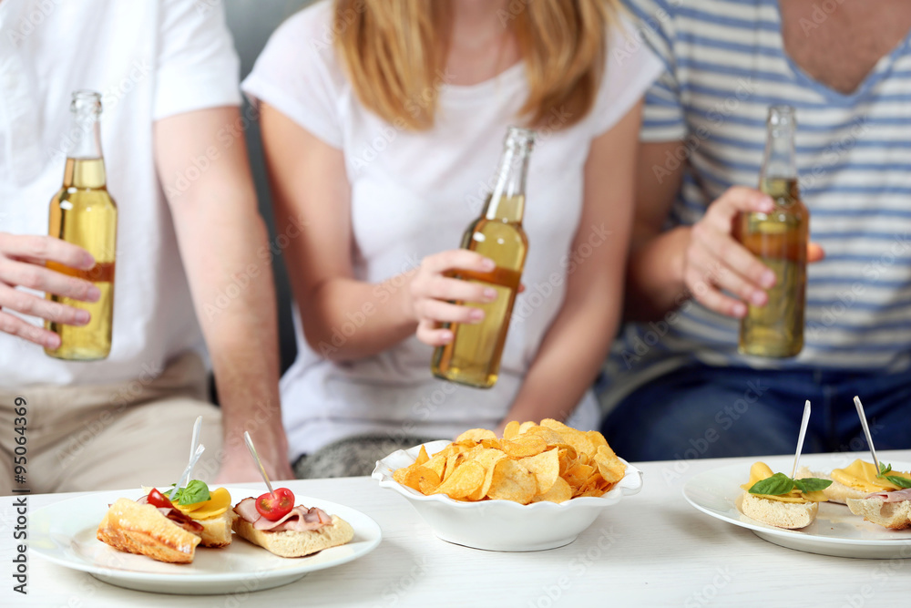 Friends hands with bottles of beer and snacks , close up