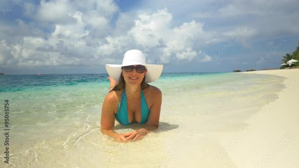 Cheerful young brunette lying in the water on exotic beach Cheerful young brunette lying in the water on exotic beach