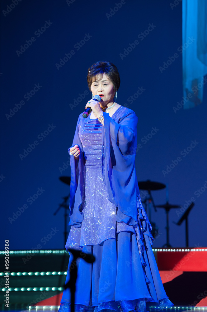 ステージの上でドレスを着て歌うシニア女性