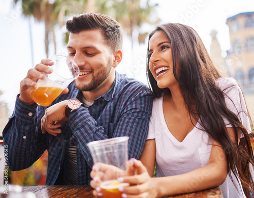 Vászonkép hispanic couple drinking beer on date together at outdoor patio