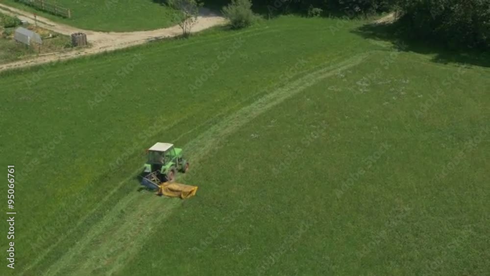 AERIAL: Tractor mowing on a grass field