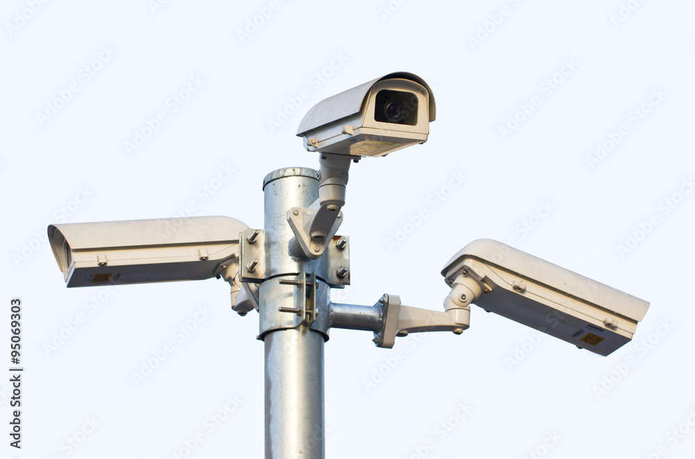 Three security cameras against the blue sky.