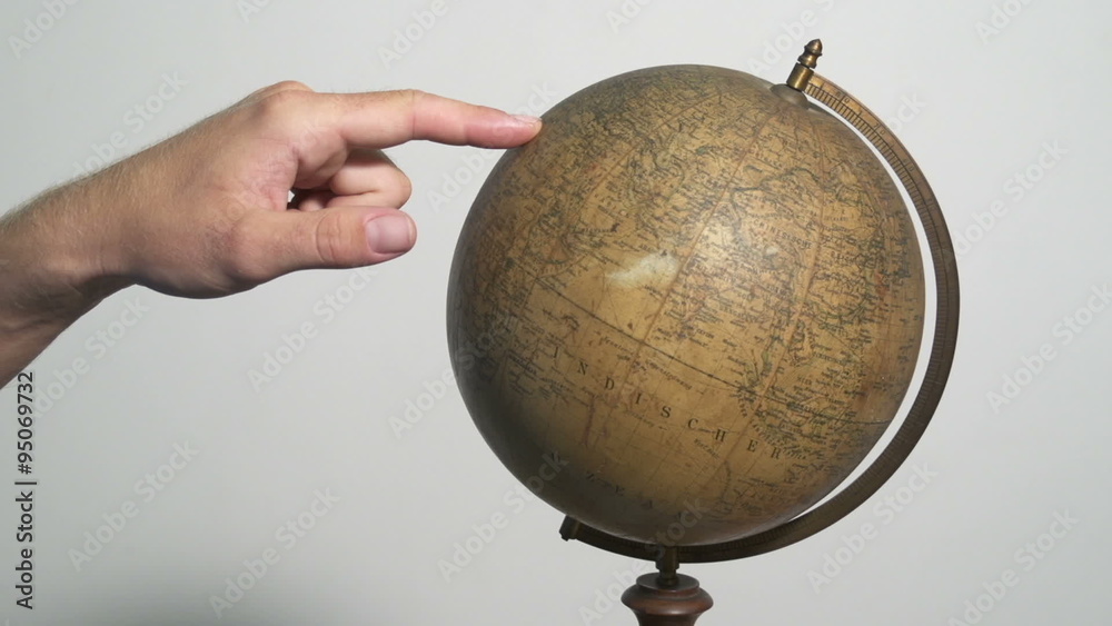 Man spinning a globe and pointing on it