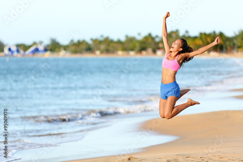 Fotografi Excited woman jumping at beach