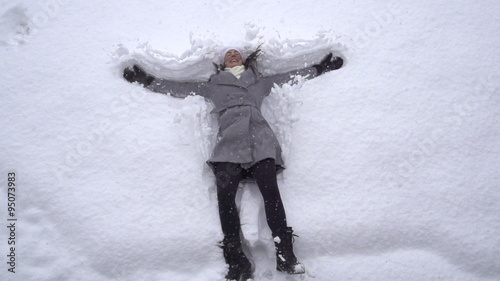SLOW MOTION: Young woman making snow angels photo