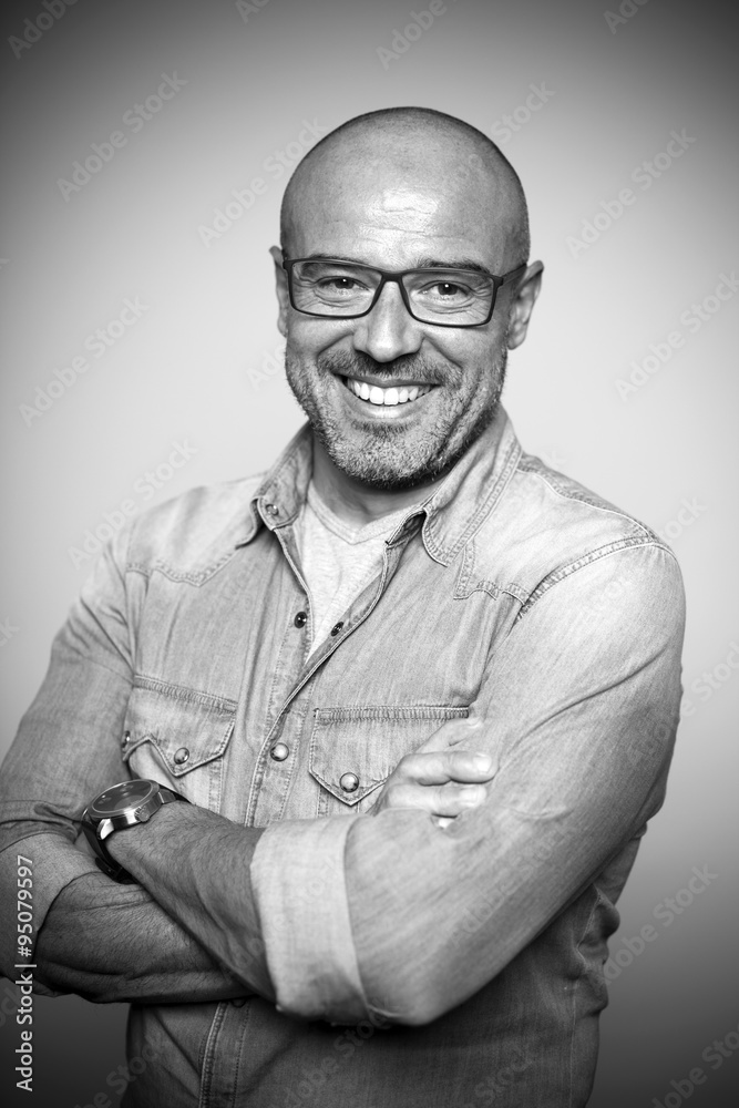 Hombre calvo de mediana edad con gafas rojas sonriendo. Blanco y negro.  Stock Photo | Adobe Stock