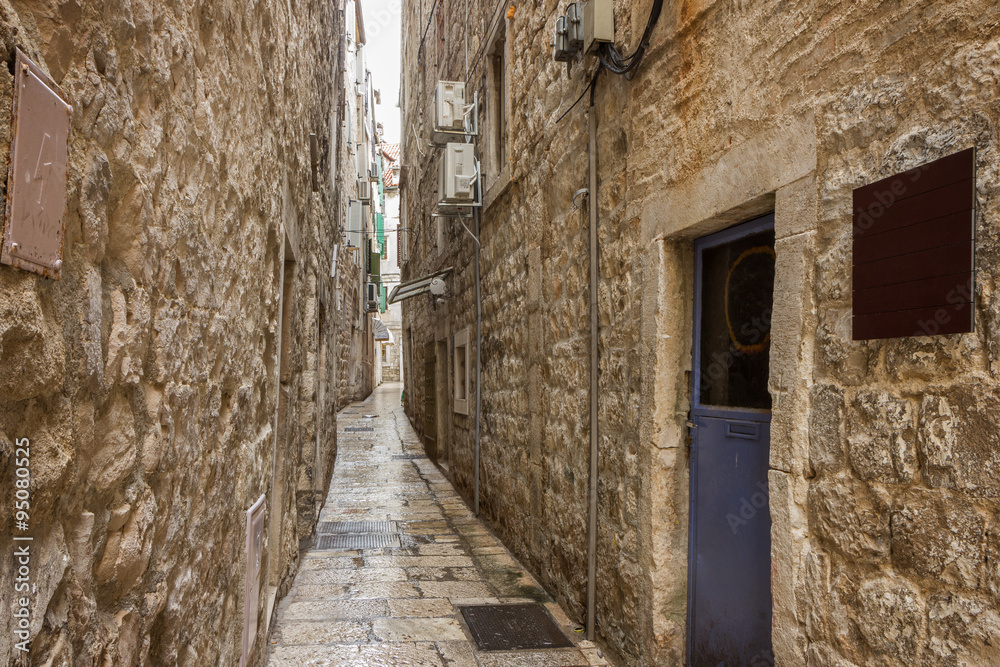 Narrow, empty and wet alley or pedestrian street at the Old Town in Split, Croatia.