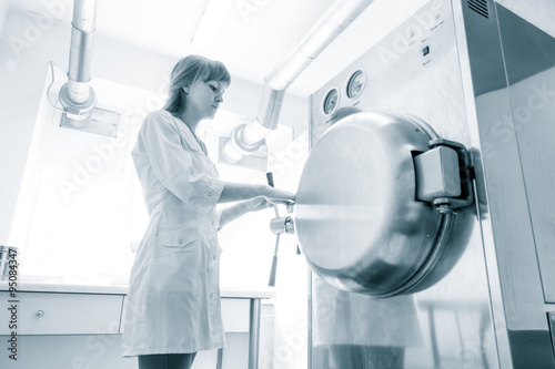 pharmaceutical factory woman worker operating autoclave for medi photo