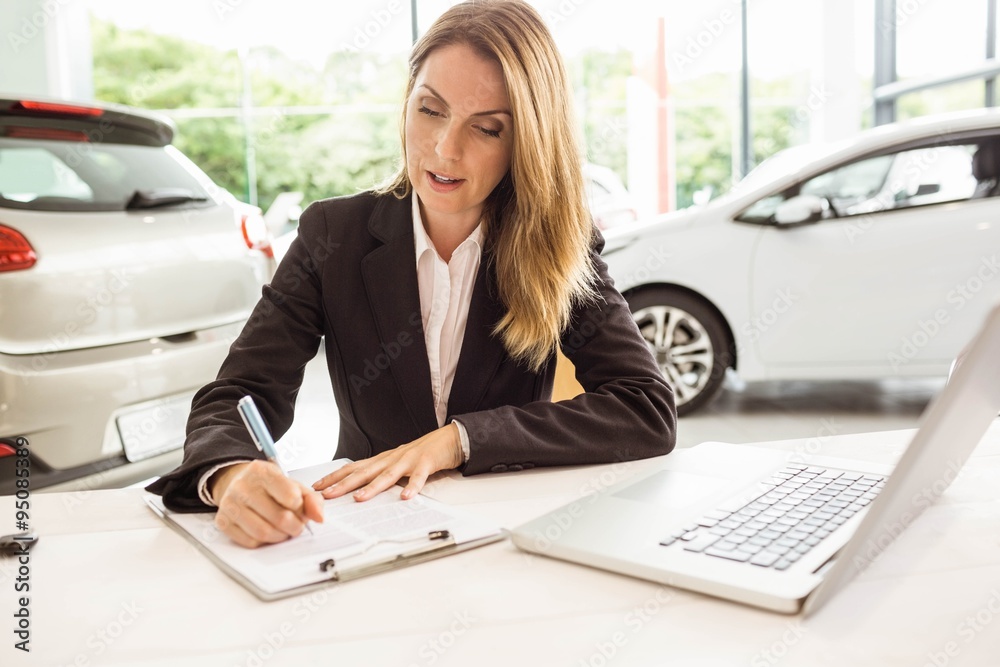 Smiling saleswoman writing on a clipboard Smiling saleswoman writing on a clipboard