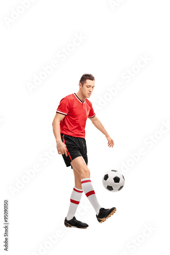 Young male football player juggling a ball