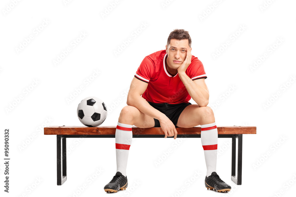 Naklejka premium Sad young football player sitting on a bench