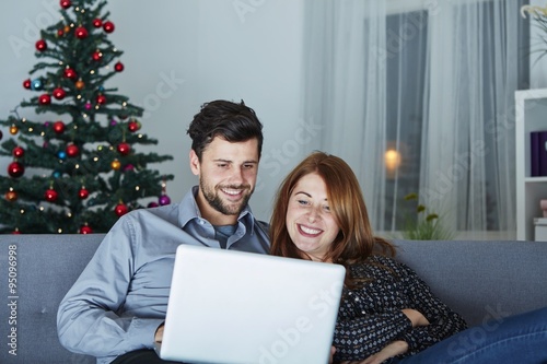 happy couple look on laptop pc for christmas