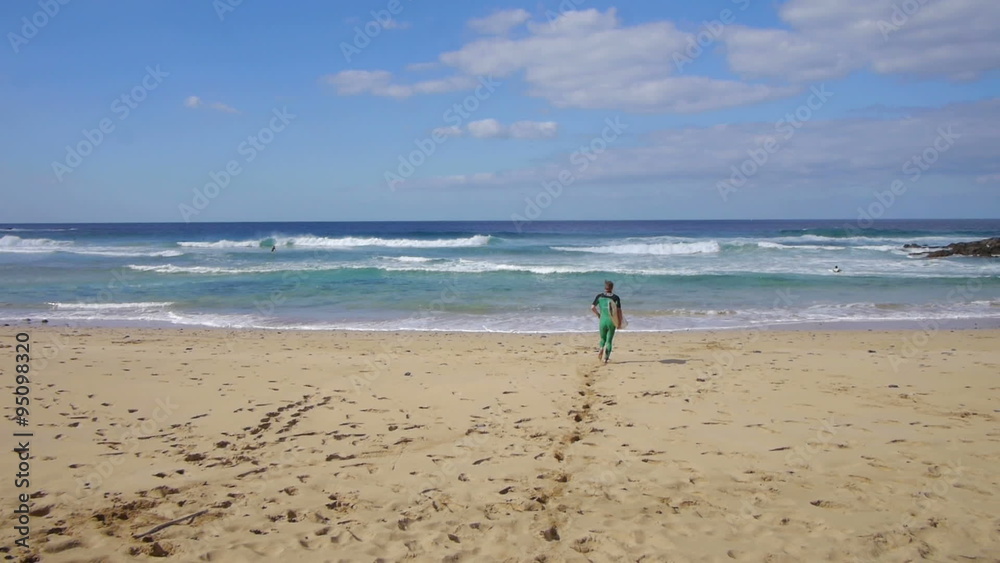 AERIAL: Surfer running into the sea AERIAL: Surfer running into the sea