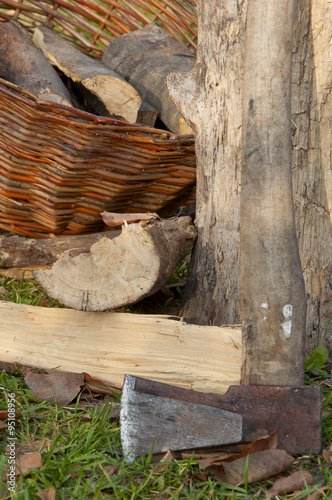 chopped firewood stacked in a basket with an ax