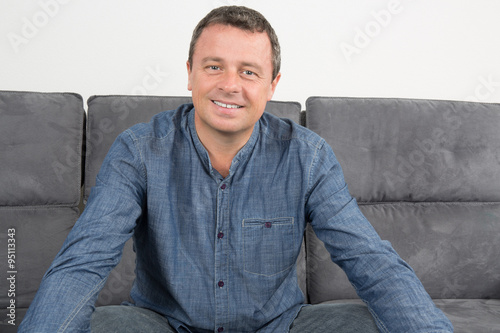 Handsome and smiling man sitting in couch