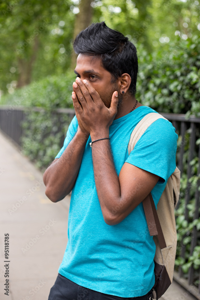 young indian man in the street looking worried