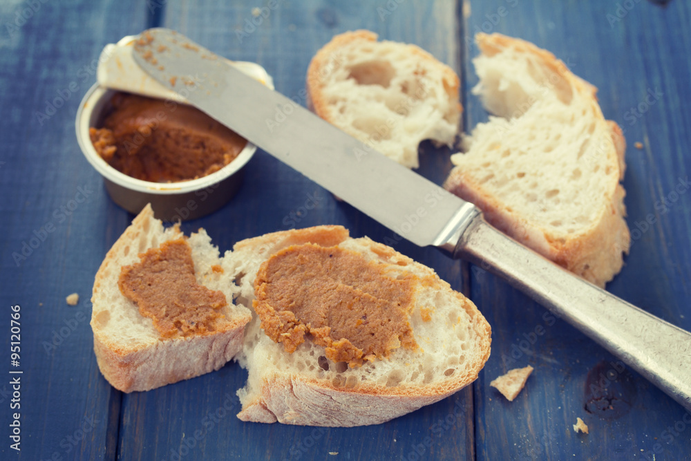 bread with fish pate and knife on blue wooden background