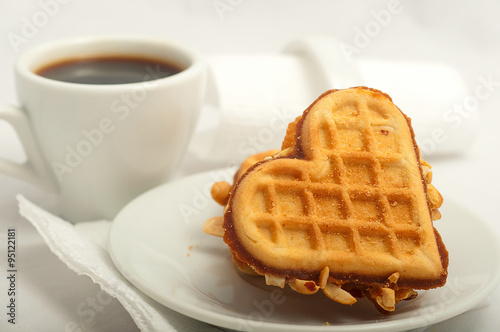cup of morning coffee and fresh waffles in the shape of heart on