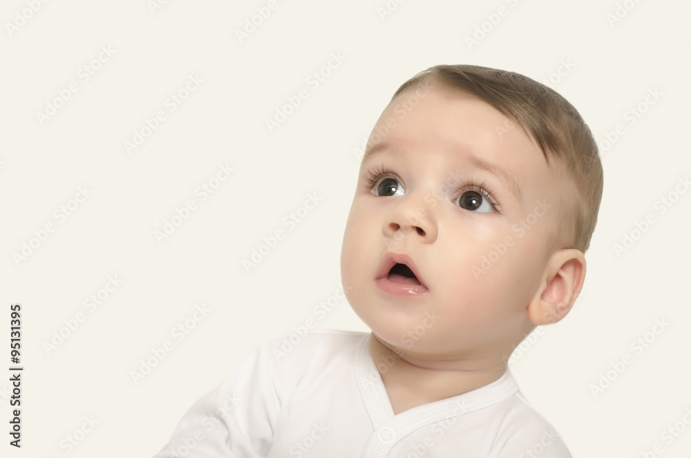 Cute baby boy looking up surprised. Adorable baby portrait looking curious isolated on white.