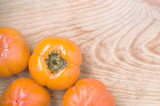Ripe fresh washed persimmons on rustic wooden board with place for text