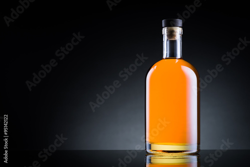 Whiskey bottle on black glass surface