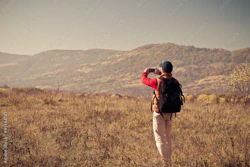 Male tourist with backpack taking pictures of  scenery to your s
